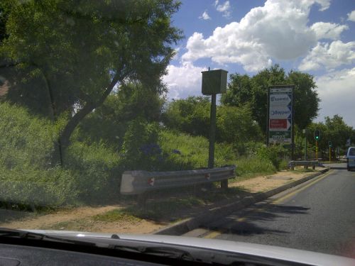 真ん中に立っている緑色のポール状のものが、スピードカメラです。周りの木と同系色で、気づきにくいようになっています。上部の四角い部分に、カメラが内蔵されています。