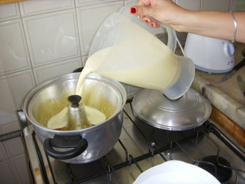 カラメルを全体に伸ばしたプリン型に混ぜた材料を注ぎ入れるところ