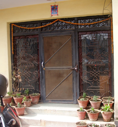 玄関扉横のガラス戸にはほら貝と壷のチベタン吉祥文様。