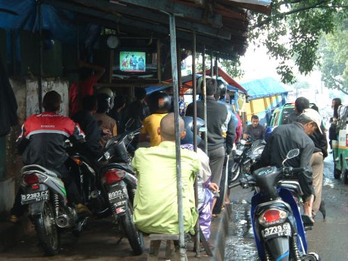 道端でサッカー観戦するバイクタクシーの運転手たち。大きな試合があると大勢集まってきます