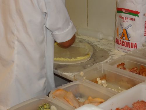 ピザ生地の縁にカトゥピリを絞り出した後、端を内側に折り込んでいる様子