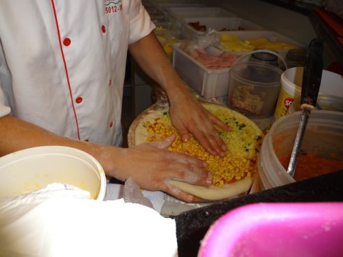 縁にカトゥピリ入りのピザ生地に具をトッピングしている様子