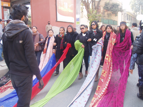 黒い影が女性のサリーに手を伸ばそうとしているデモ隊のパフォーマンス。