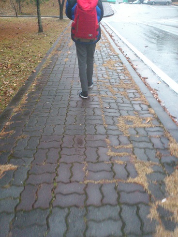 雪のチラつく中、サンダルを引きずり歩く少年