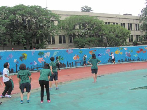 校庭にある工事用フェンスに貼られた絵をバックに……