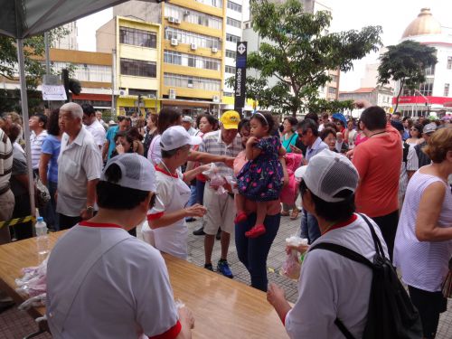 サンパウロ市の第43回餅つき祭りで、弱者優先のブースで餅の入った袋を受け取る人