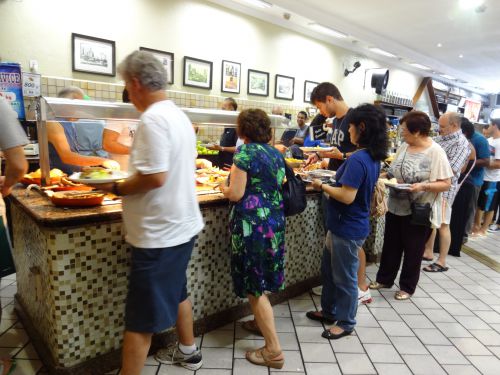 ポルキロのレストランでお皿やお持ち帰り用のアルミパックに料理を入れている人々