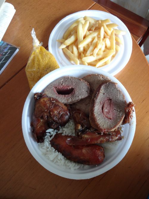 牛、鶏、リンギッサ（豚肉の腸詰）の盛り合わせとフライドポテト、ご飯、フェイジョン、ファロッファがセットになったブラジル食のお弁当