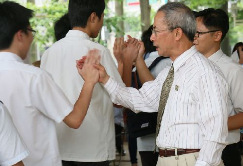 卒業生とハイタッチを交わす卓俊辰（ズオ・ジュンチェン）校長（右から2人目）
