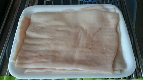 スーパーで買った豚皮はこれで約100円。臭みけしのローリエや味噌などを入れたお湯で約10分煮込んでから皮の内側の脂を包丁で削ぎ、その後焼きます