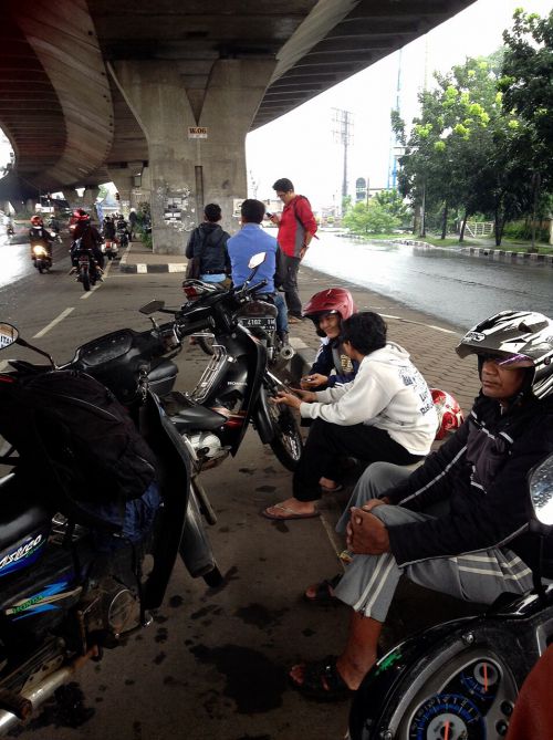 突然の雨で、高架下で雨宿りするライダーたち