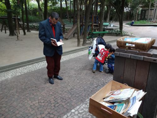 『サンパウロ市立公園で文学への誘い』で、本を手に取って立ち読みする通りすがりの男性