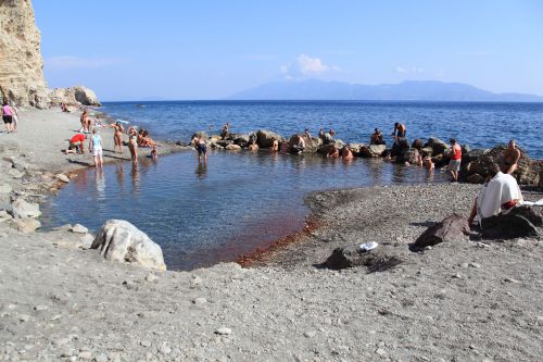 石で囲った場所に噴出す温泉で、温まる観光客たち。