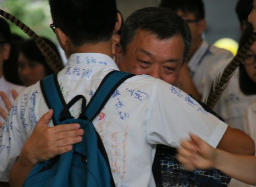 卒業生と抱擁を交わす洪仁進（ホン・レンジン）校長（右）