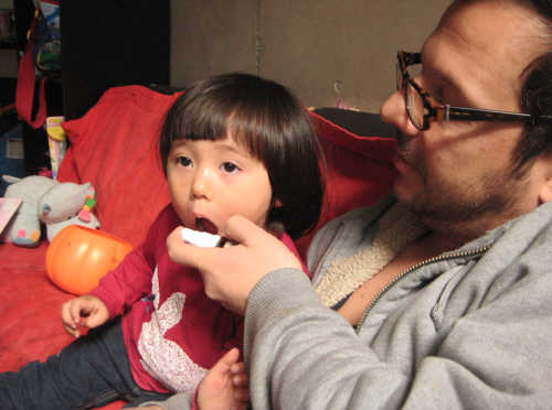 嫌がる娘になんとかプロポリススプレーをする父。