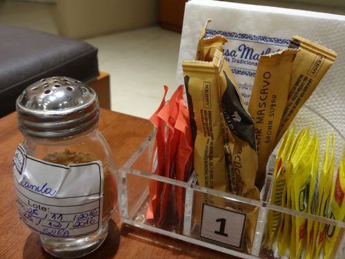 サンパウロ市内のポルトガル菓子専門店カーザ・マチルデの店内で、各テーブルに砂糖の横に置かれたシナモンの入った小瓶。賞味期限も書かれている。