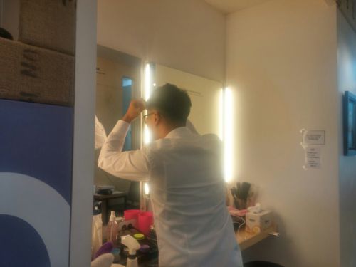 履歴書用写真撮影前にスタジオの鏡台とスプレーで髪を整える