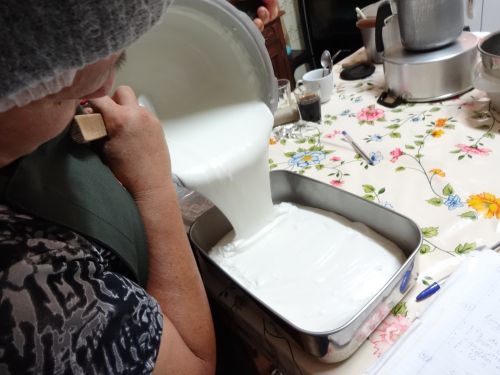 鍋で煮たピーナッツ豆腐の原料を型に流し入れるところ。