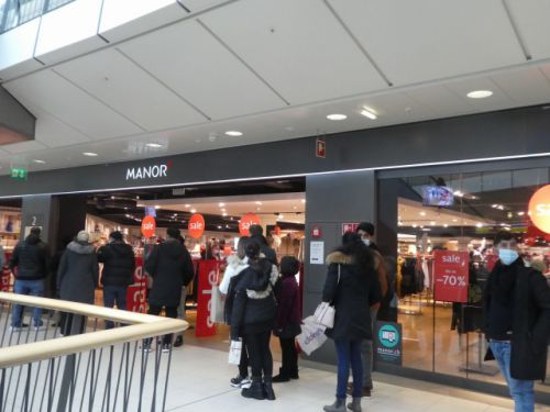 入店制限のため、店の入り口で待つ人々も